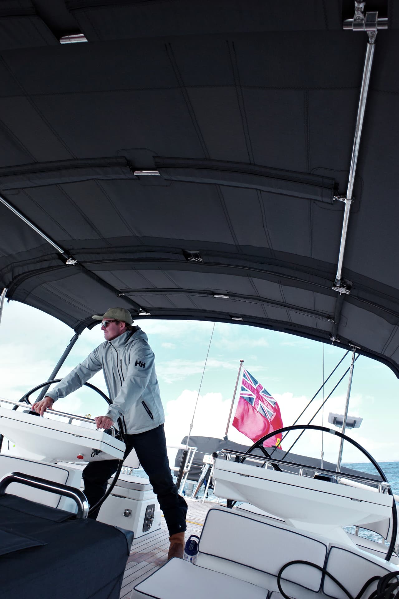 A captain at the helm of a sailing yacht under a bimini canopy